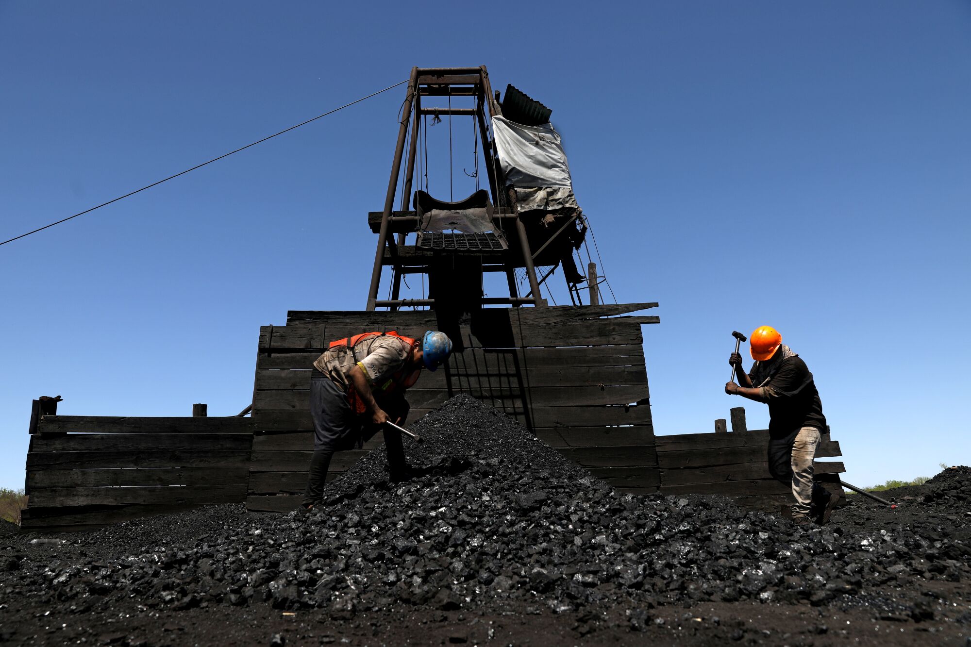 Miners break up pieces of coal.