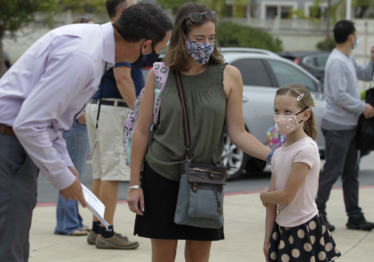 Principal Ryan Stanley, left, welcomes 2nd grade student Maeva Chappaz, with her mother Amelie Chappaz at Ocean Air School