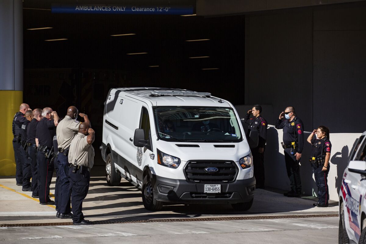 Harris County Medical Examiner van exits the Memorial Hermann Hospital transporting a Harris County Pct. 4 deputy who was shot and killed to the Harris County Institute of Forensic Sciences, Saturday, Oct. 16, 2021, in Houston. Three constable deputies were shot in an ambush early Saturday morning while working an extra shift at a Houston bar. Authorities took one person into custody but were still searching for a man believed to be the shooter, Houston Police Executive Assistant Chief James Jones told reporters. (Marie D. De Jesús/Houston Chronicle via AP)