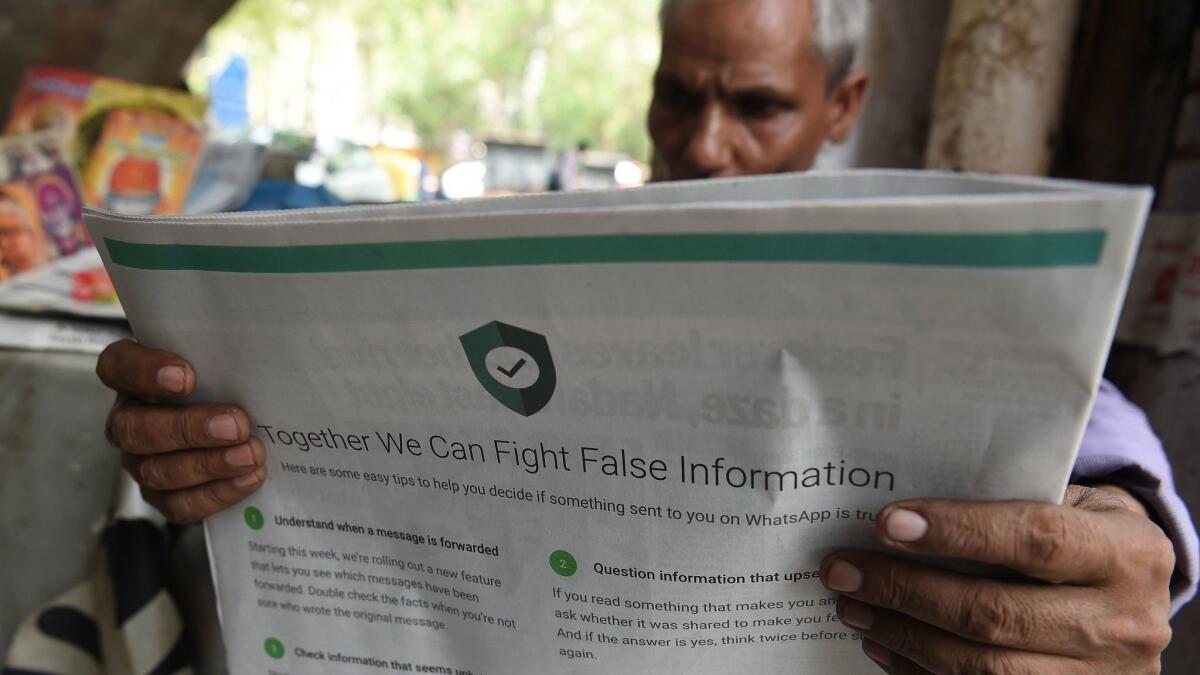 An Indian newspaper vendor in New Delhi in July reads a paper carrying a WhatsApp ad intended to counter false information.