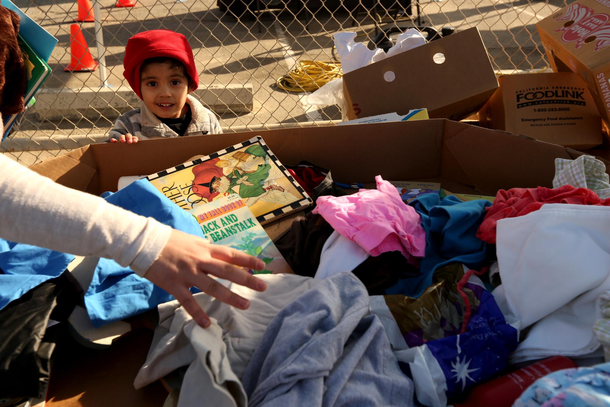 A young boy looks at a box of free clothing and books
