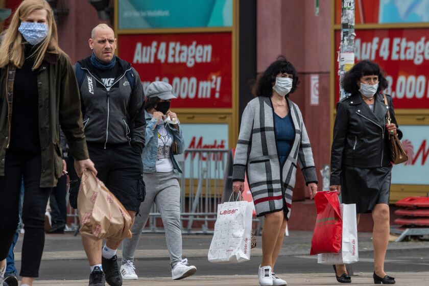 Shoppers wearing face masks walk out of a shopping mall in Berlin on April 29, 2020 amid the new coronavirus COVID-19 pandemic. - Face masks have been made mandatory in shops all over Germany. (Photo by John MACDOUGALL / AFP) (Photo by JOHN MACDOUGALL/AFP via Getty Images)