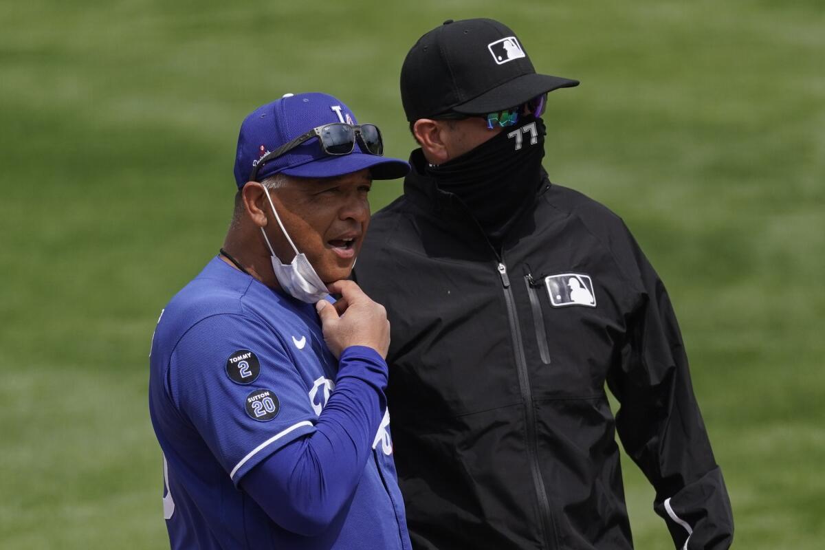 Dodgers manager Dave Roberts, left, chats with umpire Jim Reynolds before a spring training game in March.