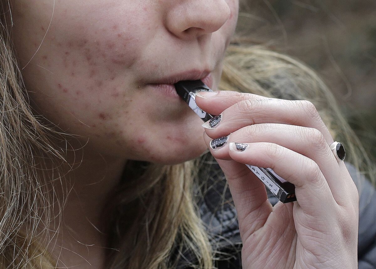A high school student uses a vaping device in Cambridge, Mass., in 2018. California lawmakers propose to ban flavored tobacco products that attract minors.