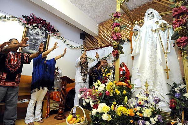 Members of Santa Muerte pray at Mass at Sanctuario Universal de la Santa Muerte, a store-front shrine on Alvarado Street in Los Angeles: "Angel created by faith, allow the power in me to be released."