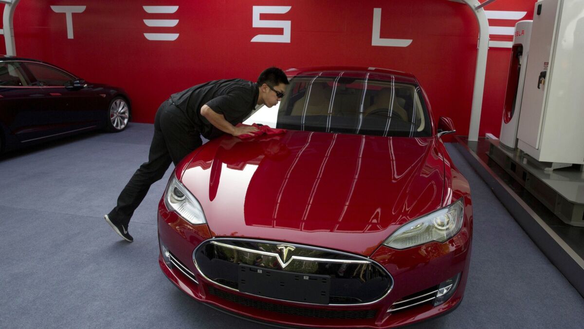 A worker cleans a Tesla Model S sedan in Beijing. Tesla plans to make small crossover SUVs at a factory in Shanghai starting in 2020.