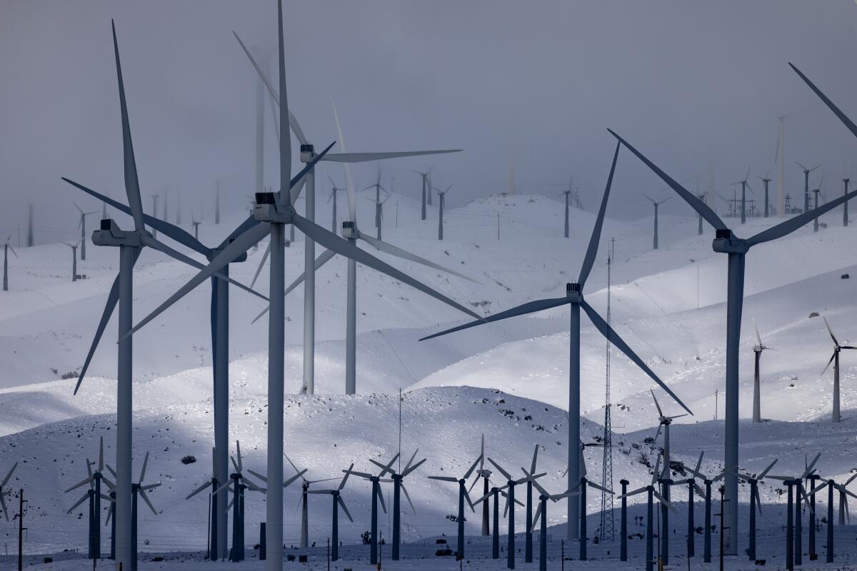 Wind turbines are surrounded by fresh snow.