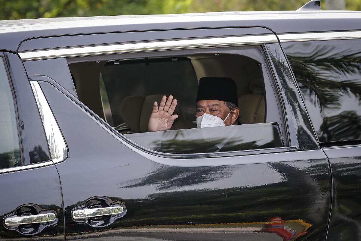 In this Aug. 4, 2021, photo, Malaysian Prime Minister Muhyiddin Yassin waves from a car while entering the National Palace to meet the king in Kuala Lumpur, Malaysia. With his last-ditch plan to seek opposition backing for his government rejected, embattled Muhyiddin appears set to resign after failing to cobble up majority support. Muhyiddin will submit his resignation to the king on Monday, Aug. 16, 2021. (AP Photo/FL Wong)