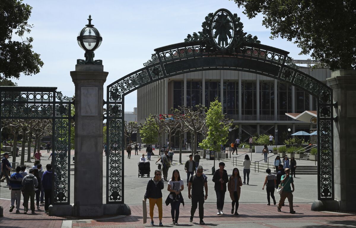 Students walk under a gate to an outdoor plaza at UC Berkeley 