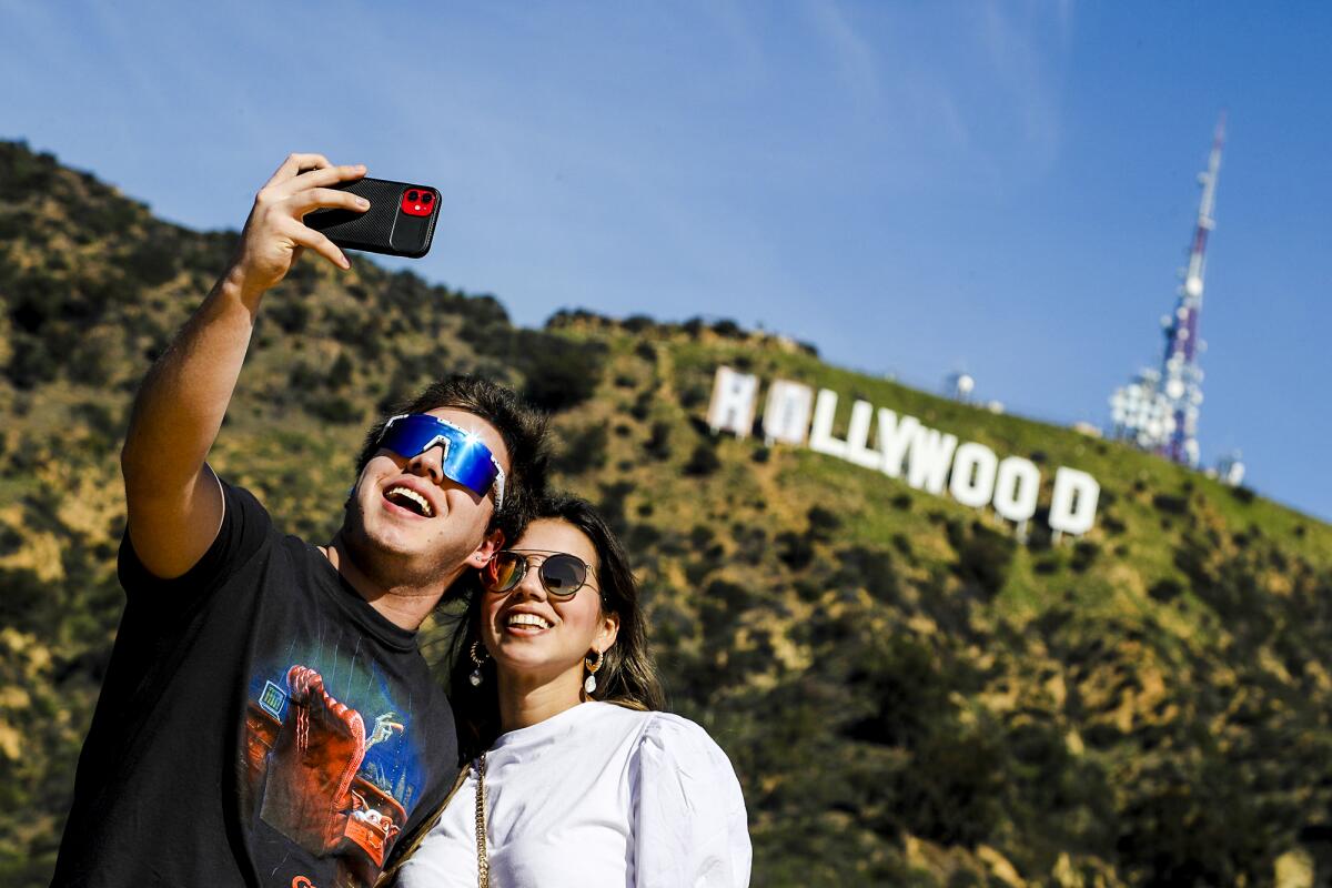 People take selfies in front of the Hollywood