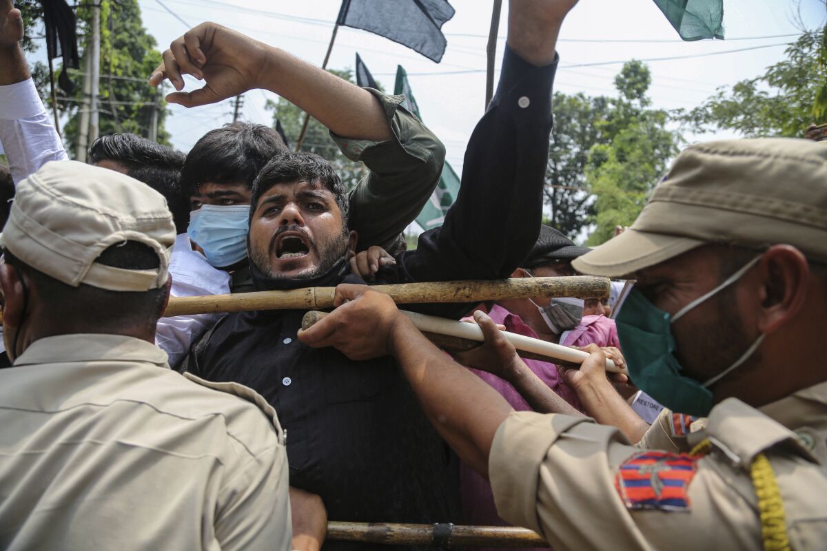 Activists of Peoples Democratic Party scuffle with police during a protest marking the second anniversary of Indian government scrapping Kashmir’s semi- autonomy in Jammu, India, Thursday, Aug.5, 2021. On Aug. 5, 2019, Indian government passed legislation in Parliament that stripped Jammu and Kashmir’s statehood, scrapped its separate constitution and removed inherited protections on land and jobs. (AP Photo/Channi Anand)