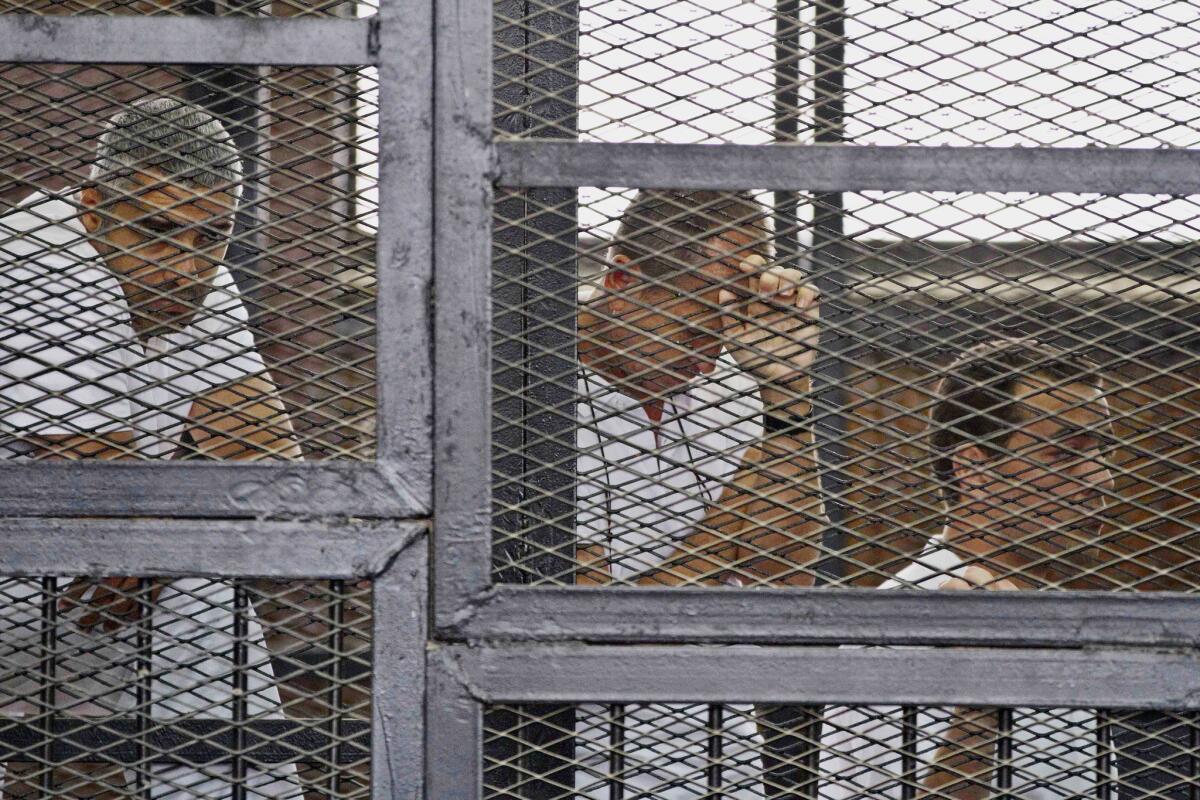 Mohamed Fahmy, left, Peter Greste, center, and Baher Mohamed appear in a defendants' cage May 15 during their trial on terror charges at a courtroom in Cairo.