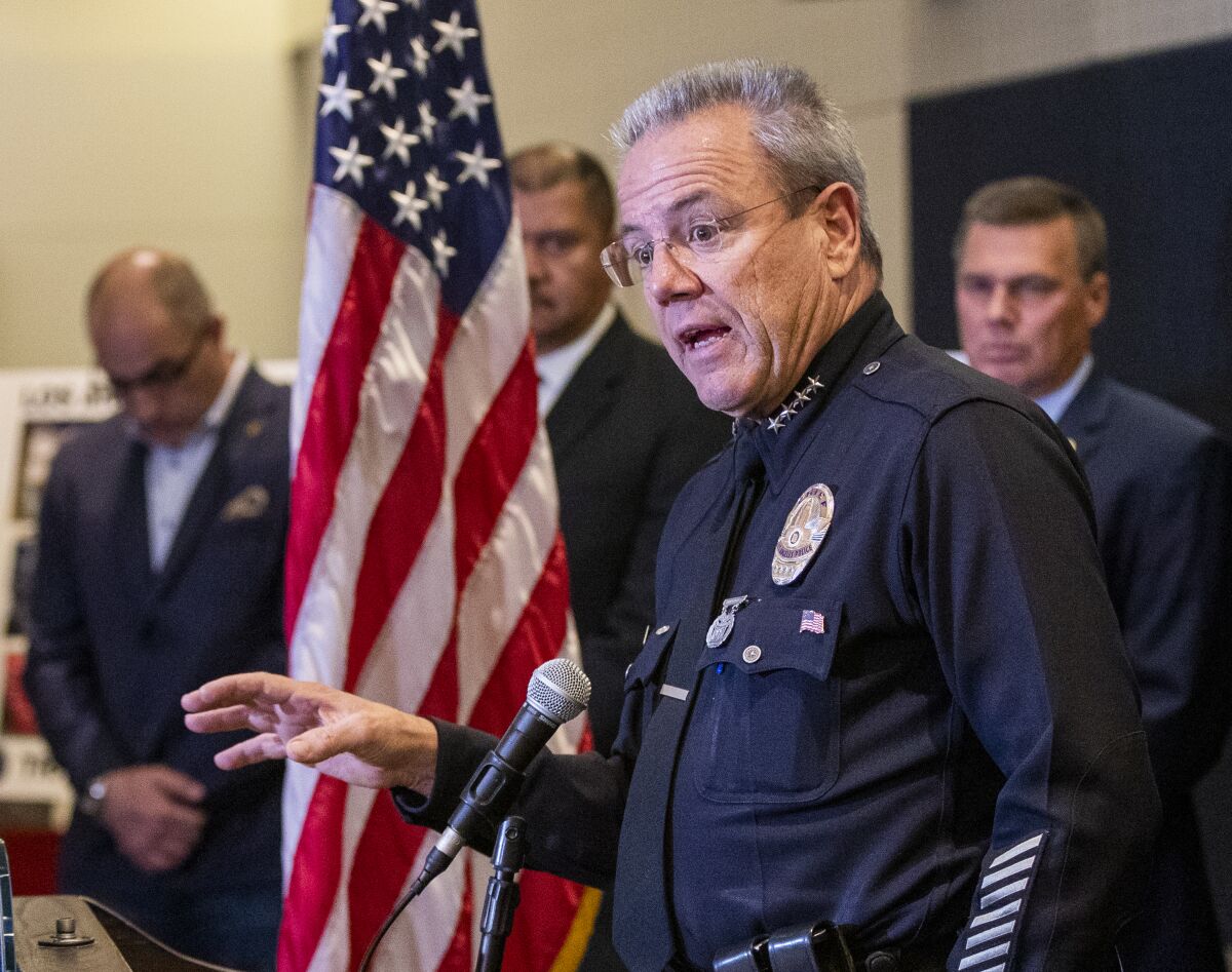 LAPD Chief Michel Moore speaks at a microphone during a news conference.