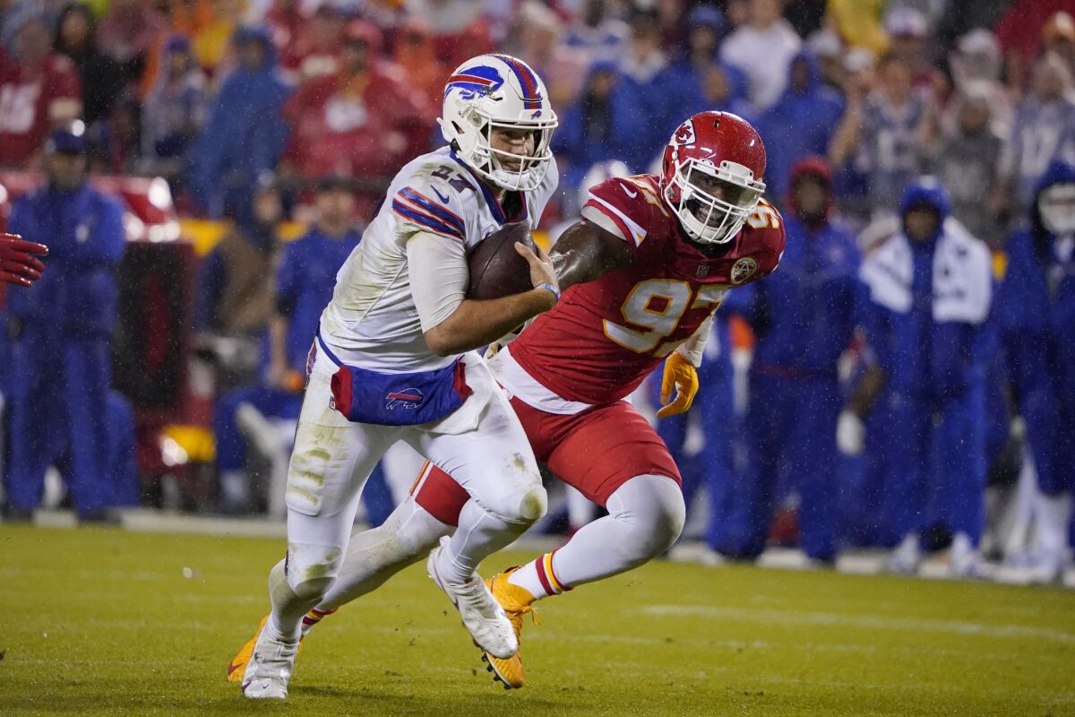 Buffalo Bills quarterback Josh Allen, left, runs with the ball as Kansas City Chiefs defensive end Alex Okafor chases him.