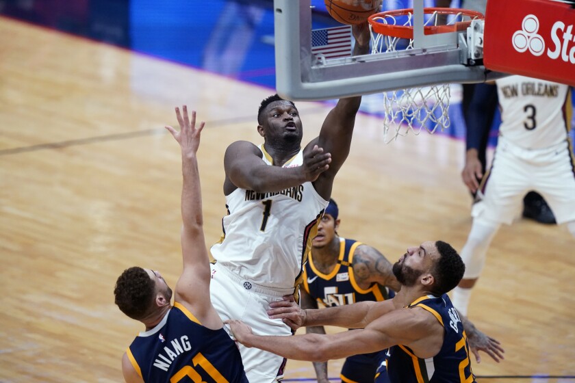 New Orleans Pelicans forward Zion Williamson (1) goes to the basket over Utah Jazz forward Georges Niang, left, and center Rudy Gobert, right, in the first half of an NBA basketball game in New Orleans, Monday, March 1, 2021. (AP Photo/Gerald Herbert)