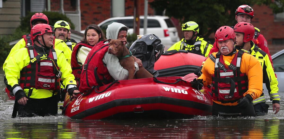 People are rescued on a red inflatable boat on a flooded street