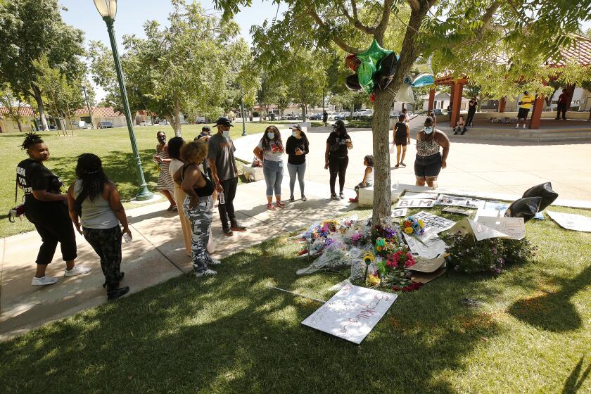 PALMDALE, CA - JUNE 15: People gather at a memorial under a tree for Robert Fuller in Poncitlan Square next to Palmdale City Hall where Fuller, a young black man was found hung last week. Nearby protestors are stationed at the doors to Palmdale City Hall which remain closed Monday morning with protestors stationed at each entry door with a sit-in at Palmdale City Hall as organizers demand justice for Robert Fuller, the young black man who was found hung in Poncitlan Square last week. The group is seeking more information on Fuller's case, including the release of the 911 call and the autopsy report. Palmdale City Hall on Monday, June 15, 2020 in Palmdale, CA. (Al Seib / Los Angeles Times)