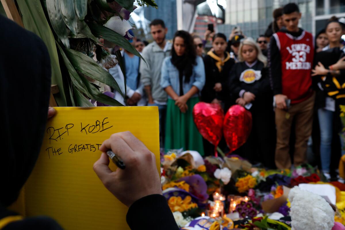 Gilbert Partida writes a note on a memorial board for Kobe Bryant in January in Los Angeles.