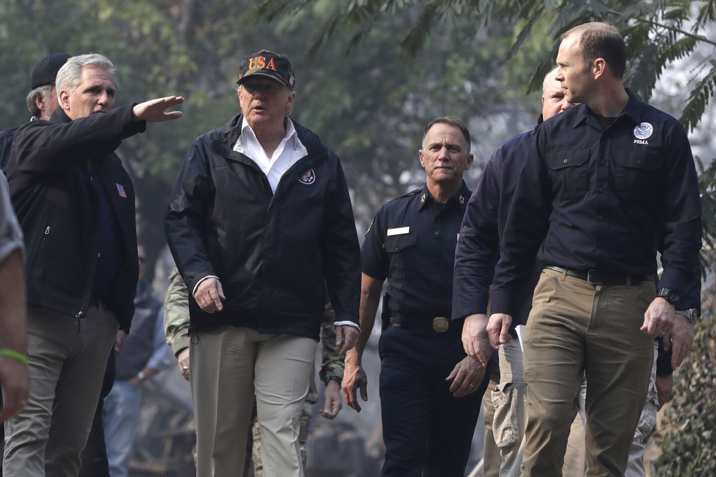 President Donald Trump walks with House Majority Leader Kevin McCarthy of Calif., left and FEMA Administrator Brock Long, right, as he visits a neighborhood impacted by the wildfires in Paradise, Calif.