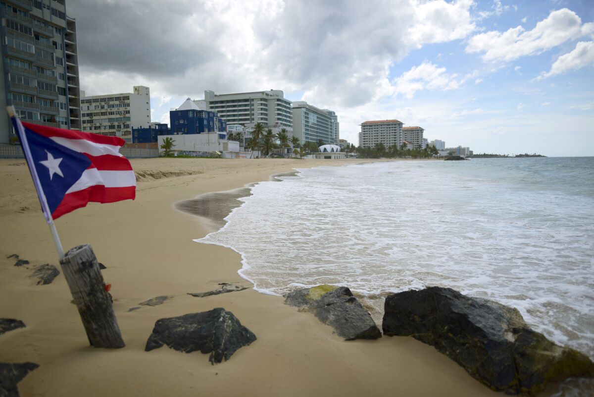 FILE - A Puerto Rican flag flies on the shore at Ocean Park, in San Juan, Puerto Rico, Thursday, May 21, 2020. A ruling by Puerto Ricos Supreme Court on Wednesday, March 15, 2023, upholds the decision of an appeals court that voids a document from 2020 that regulates land use and the granting of permits on the island, throwing into limbo hundreds of thousands of business and construction permits. (AP Photo/Carlos Giusti, File)