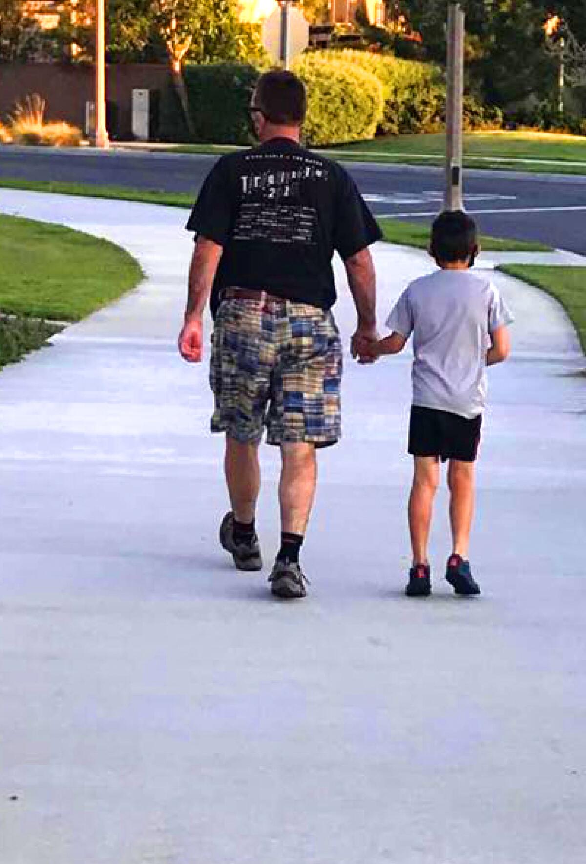 Andrew Highsmith holds his son's hand while walking. 