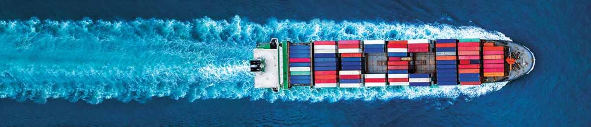 Aerial top view of container ship with contrail in the ocean