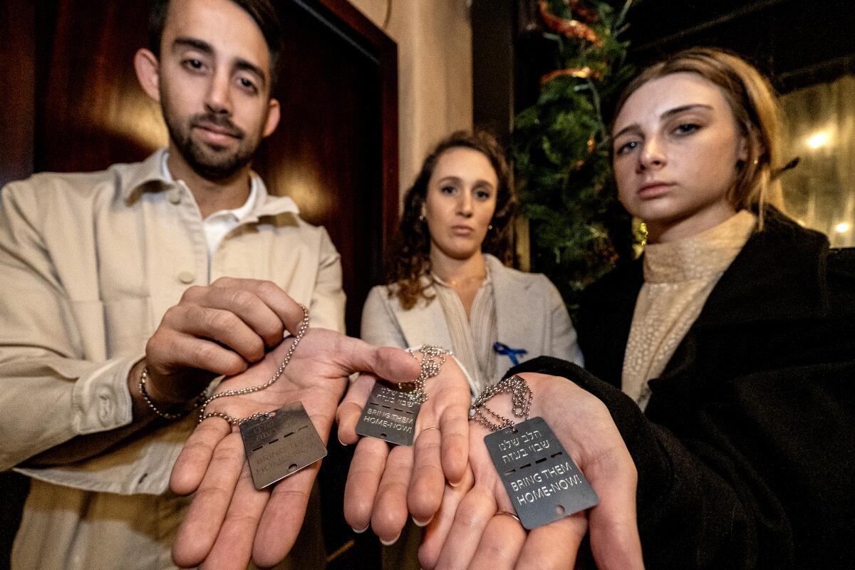 Les membres de la famille des otages israéliens Itay Raviv et les sœurs Naama et Ofir Weinberg montrent leurs plaques d'identité.