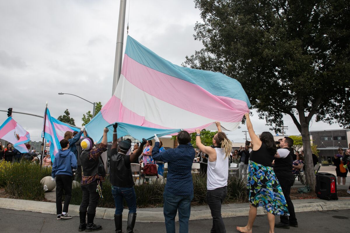 San Diego LGBT Community Center volunteers help raise the transgender pride flag.