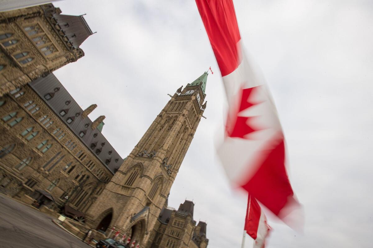 A Canadian flag waves in front of the peace tower on Parliament Hill in Ottawa.