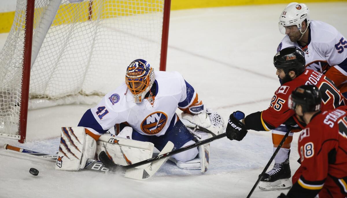 New York Islanders goalie Jaroslav Halak, left, blocks the net as Calgary's Brandon Bollig chases the puck on Jan. 2.