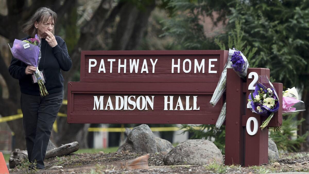 A woman reacts while placing flowers at a sign where a hostage situation with an active shooter came to a tragic end the night before at the Veterans Home of California in Yountville.