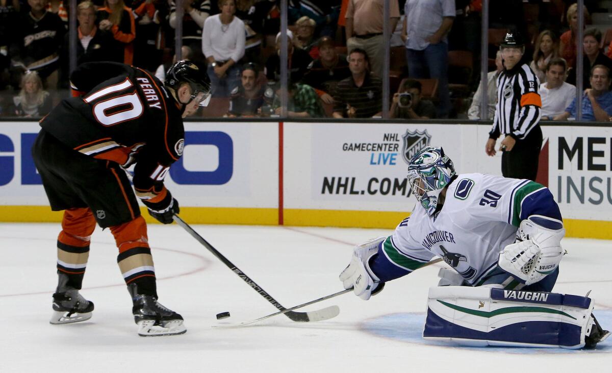 Canucks goalie Ryan Miller knocks the puck away from Ducks right wing Corey Perry in a shootout. The Canucks outscored the Ducks in the shootout, 2-1.