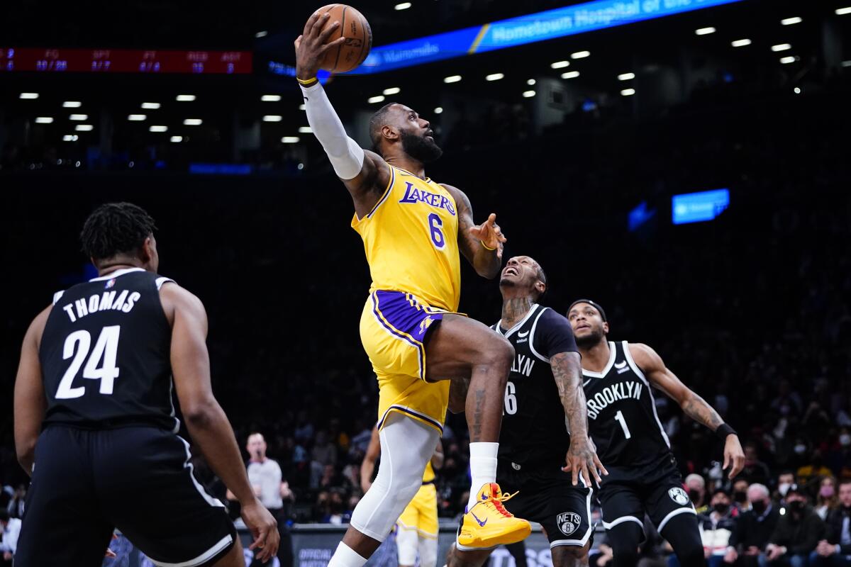 Lakers star LeBron James drives past Brooklyn's James Johnson and Cam Thomas during the first half.