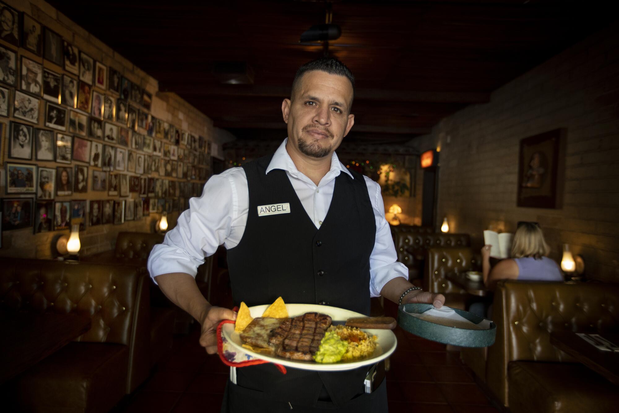 Server Miguel Angel Martinez holds the popular dinner 'Carne asada con guacamole' at Lucy’s El Adobe in Los Angeles in 2019.