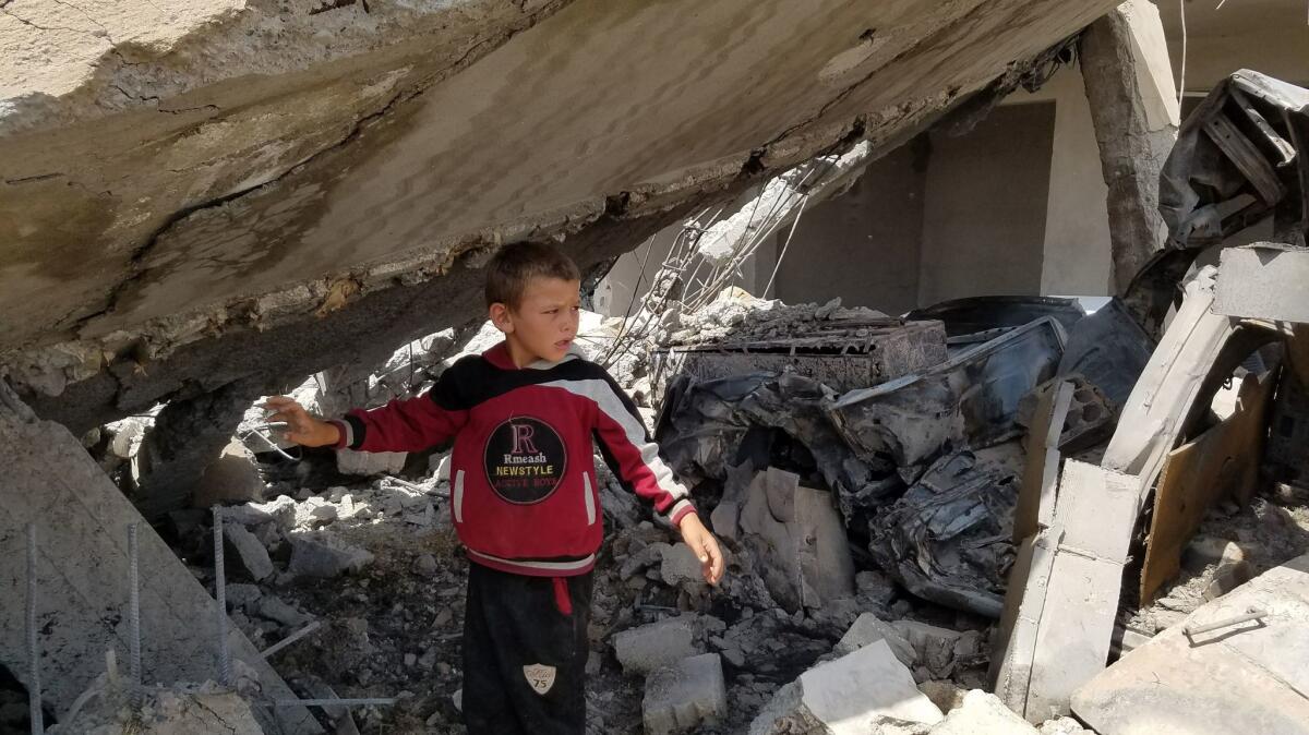 A neighborhood boy stands in the rubble of a former Islamic State jail in Mansoura, Syria.