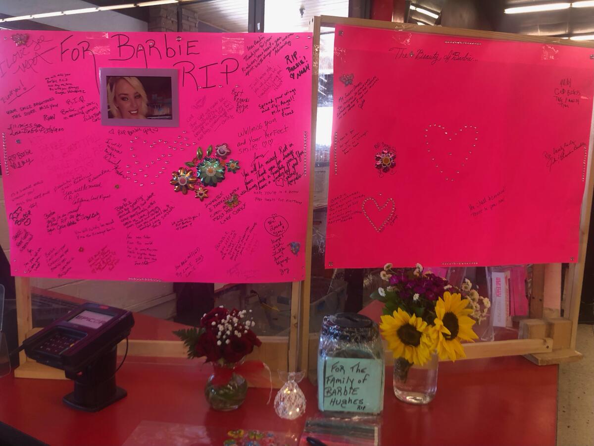 Flowers and handwritten comments surround a woman's photo on a store counter.