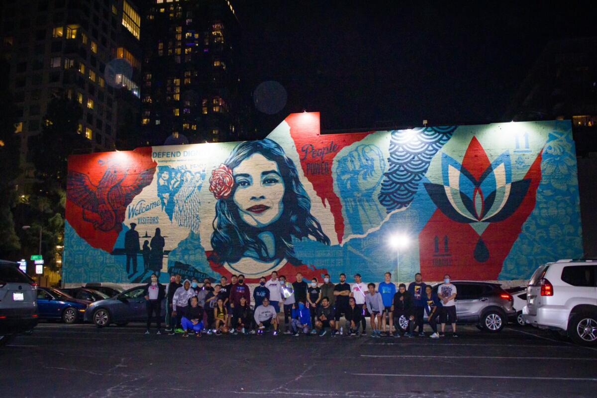 Runners pause in front of a mural at night