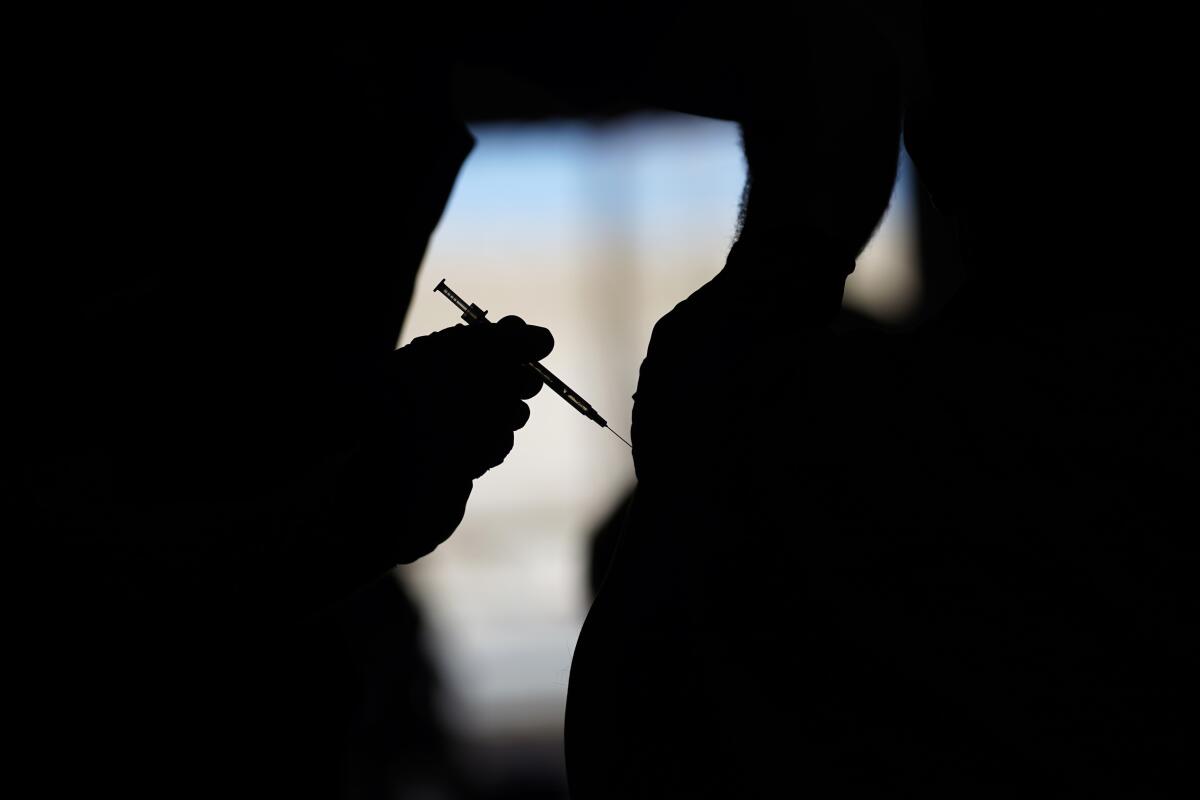 A silhouette of a man receiving a COVID-19 vaccine at a vaccination site.