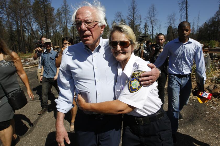 Democratic presidential candidate Sen. Bernie Sanders, I-Vermont, is hugged by Geralynne Radar, a volunteer with the Paradise Police Department, as he tours a mobile home park destroyed by last year's wildfire fire in Paradise, Calif., Thursday, Aug. 22, 2019. (AP Photo/Rich Pedroncelli)