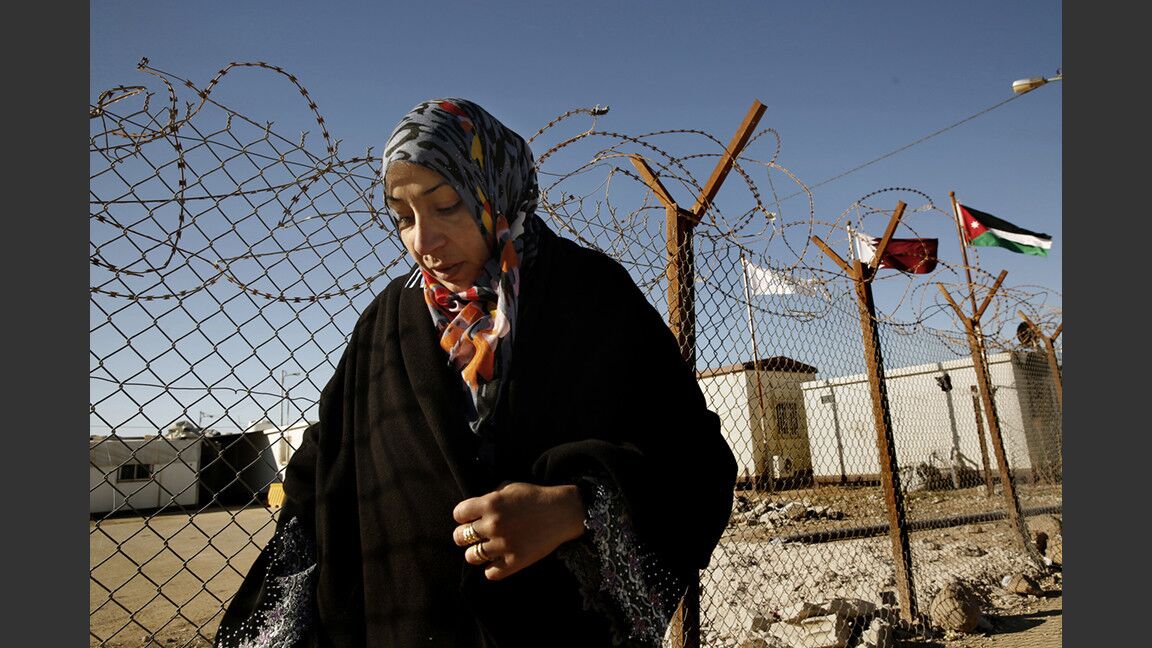 Syrian refugee Samah Qteish, a pregnant mother of two, stands at the perimeter of Zaatari refugee camp waiting for her husband. Anyone who wants to leave the camp must get approval.