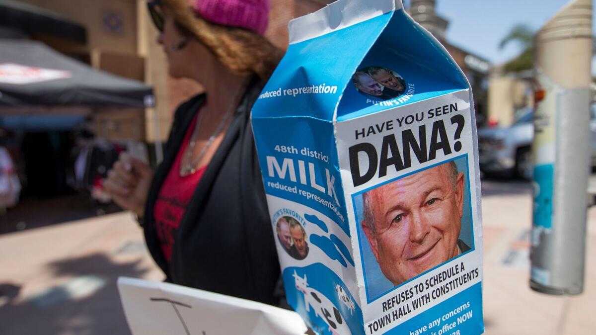 Bethany Webb, an Indivisible OC organizer, holds a milk carton bearing Rep. Dana Rohrabacher's picture at a protest outside his Huntington Beach office Tuesday.