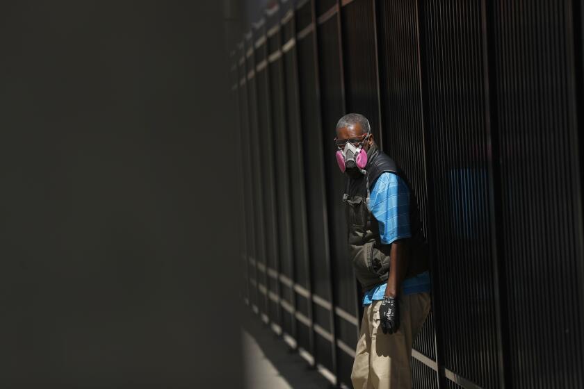A man in Detroit wears a protective mask while waiting for a bus.