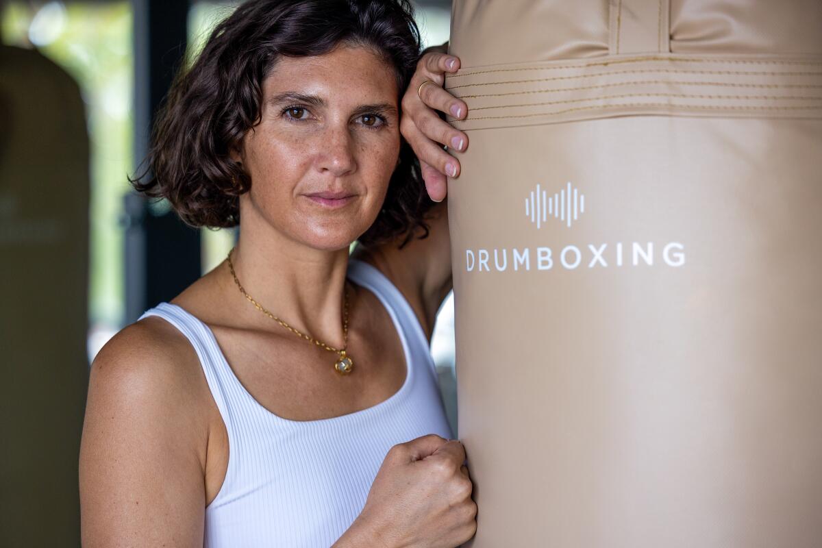Drumboxing co-founder Christina Hines poses with a punching bag emblazoned with the Drumboxing logo.