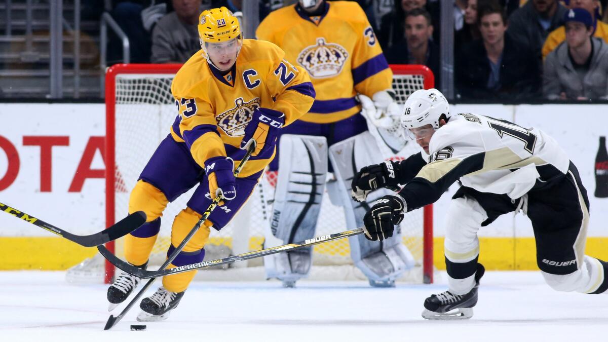 Kings captain Dustin Brown, left, controls the puck in front of Pittsburgh Penguins forward Brandon Sutter during the Kings' 1-0 overtime loss at Staples Center on Saturday.