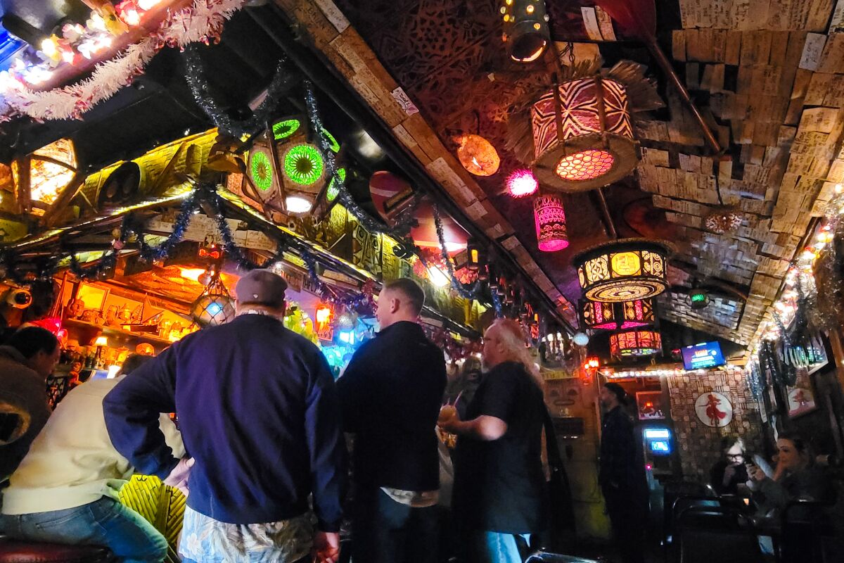 Glowing, colored lamps illuminate a bar's riotously decorated ceiling.