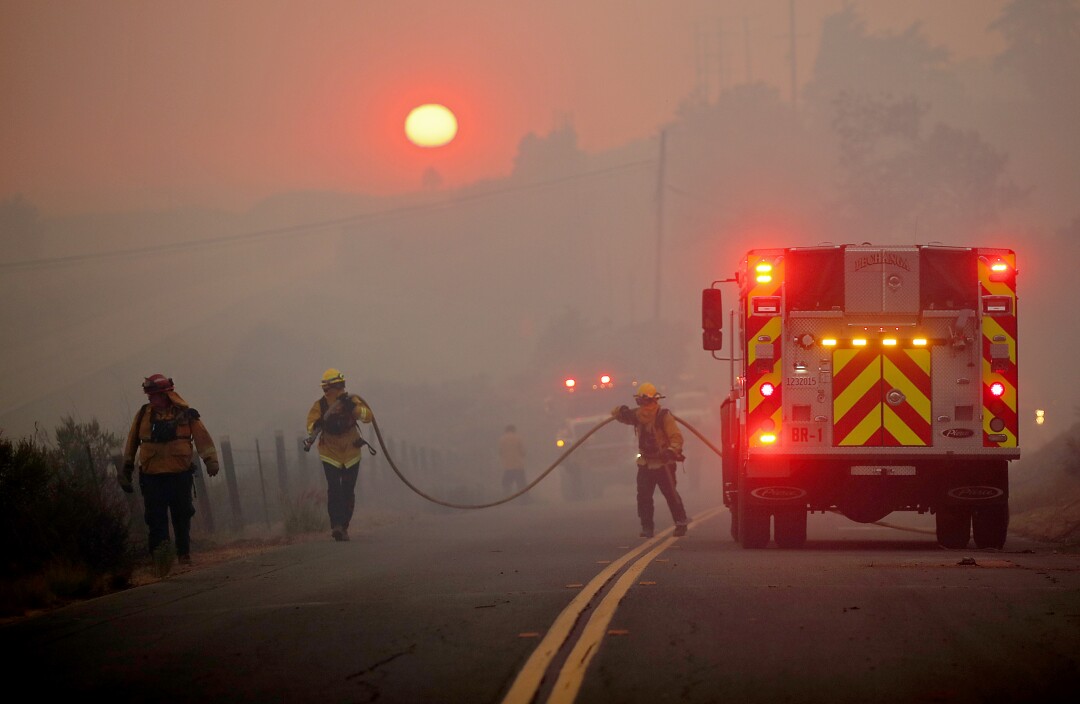 Firefighters carry hose