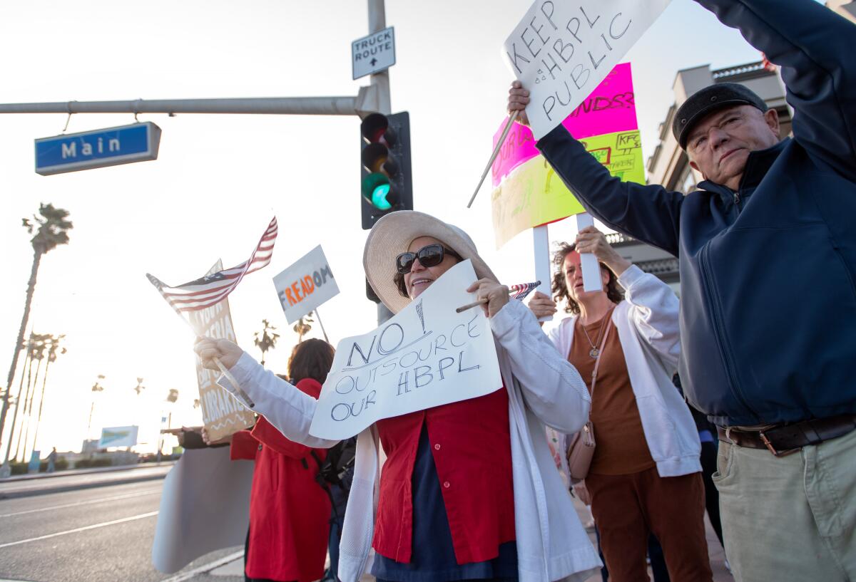 Jose and Elena Uranga wave signs and join in chants in protest in Huntington Beach on Friday.