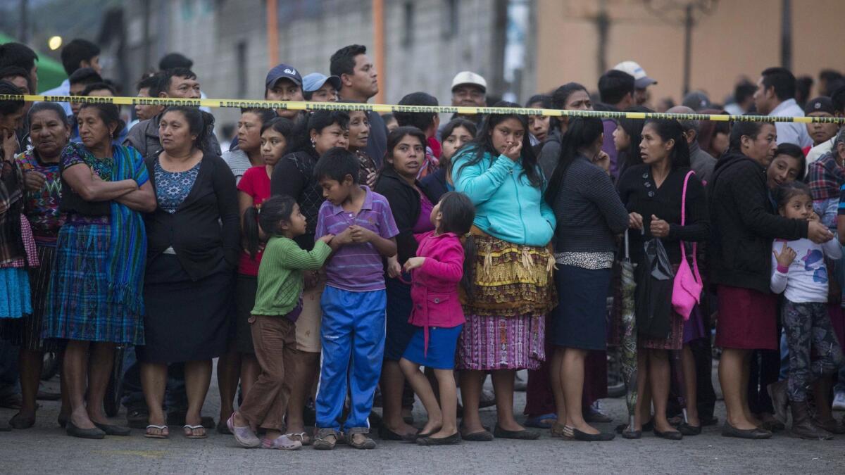 Residents stand outside a temporary morgue near the Volcan de Fuego, or Volcano of Fire, in Alotenango, Guatemala, on Sunday.