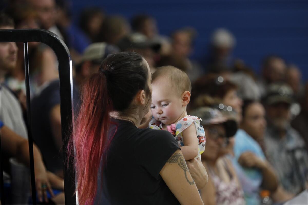 Trona resident Casey Huggins holds her friend's baby, Allison Jordan, during Wednesday's town hall meeting. Huggins' home is no longer habitable after twin earthquakes rocked the area last week.