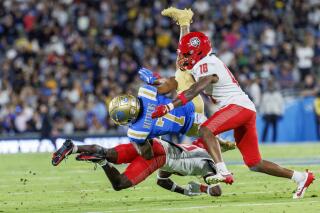 UCLA wide receiver Mikey Matthews is upended by New Mexico cornerback Jon Johnson and safety Caleb Coleman.